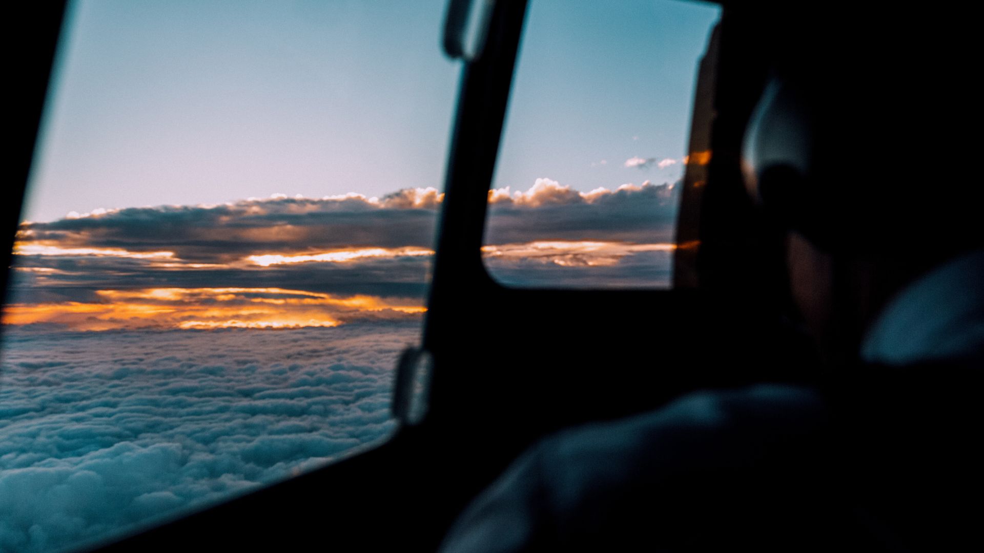 Sunrise view from airplane window over cloudy sky and horizon