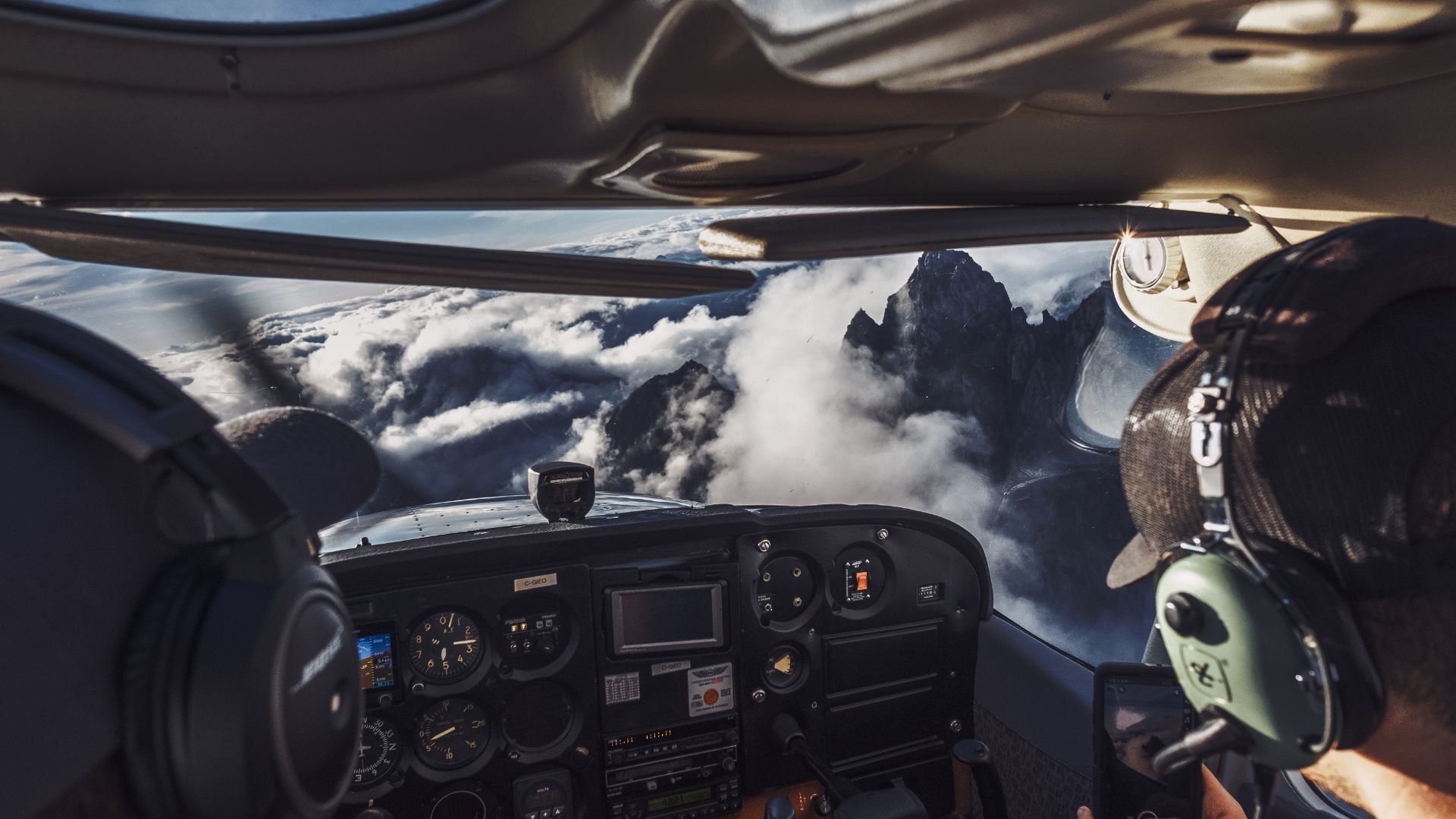 Pilot's view of rocky mountain peaks emerging from cloudy sky