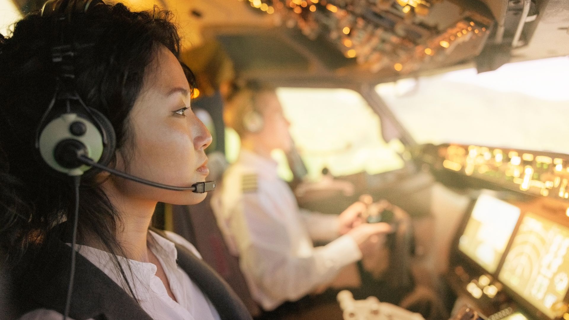 Pilot wearing headset in cockpit, golden sunlight illuminating airplane controls