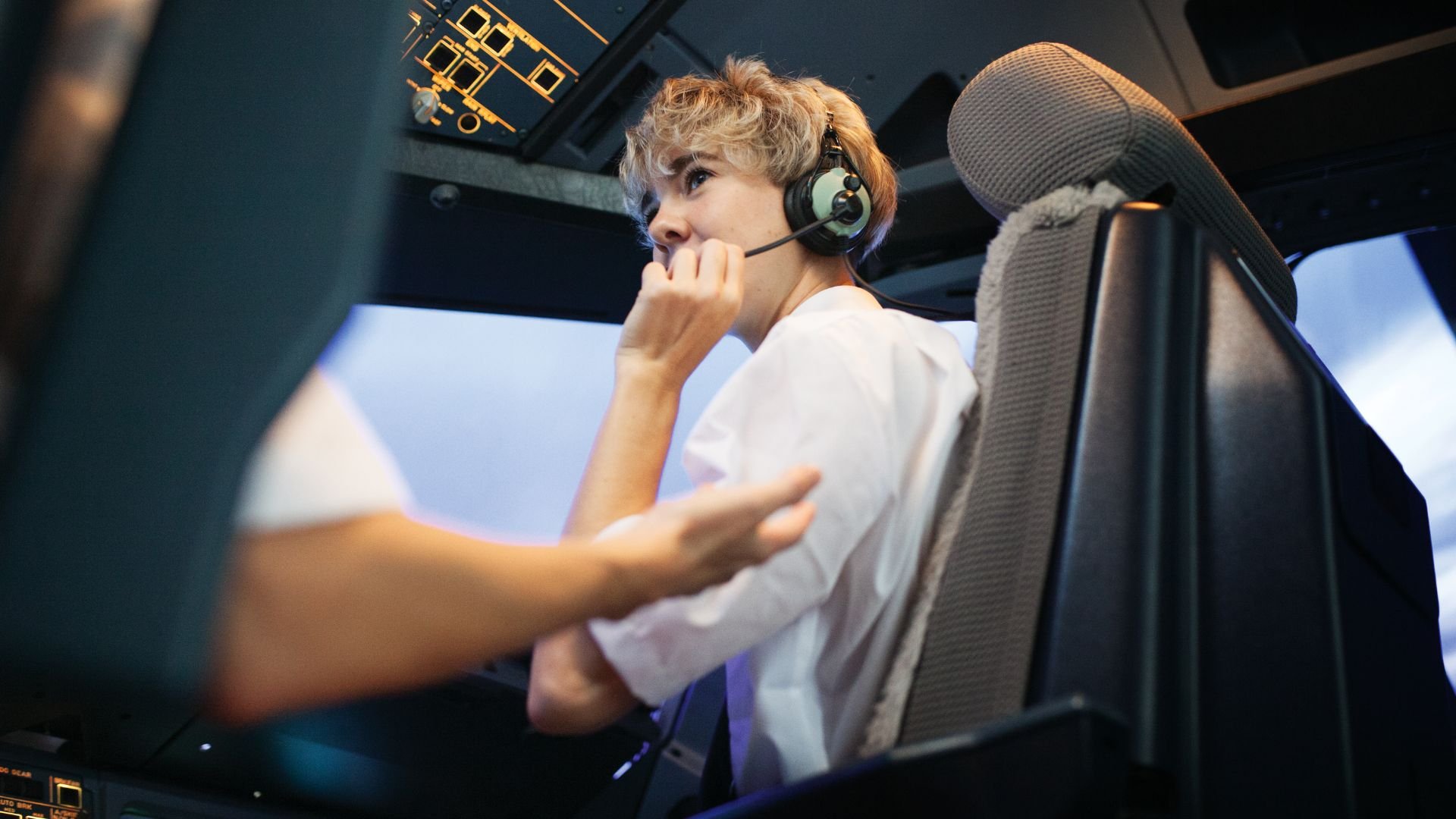 Pilot with headset sitting in cockpit, looking thoughtful and focused