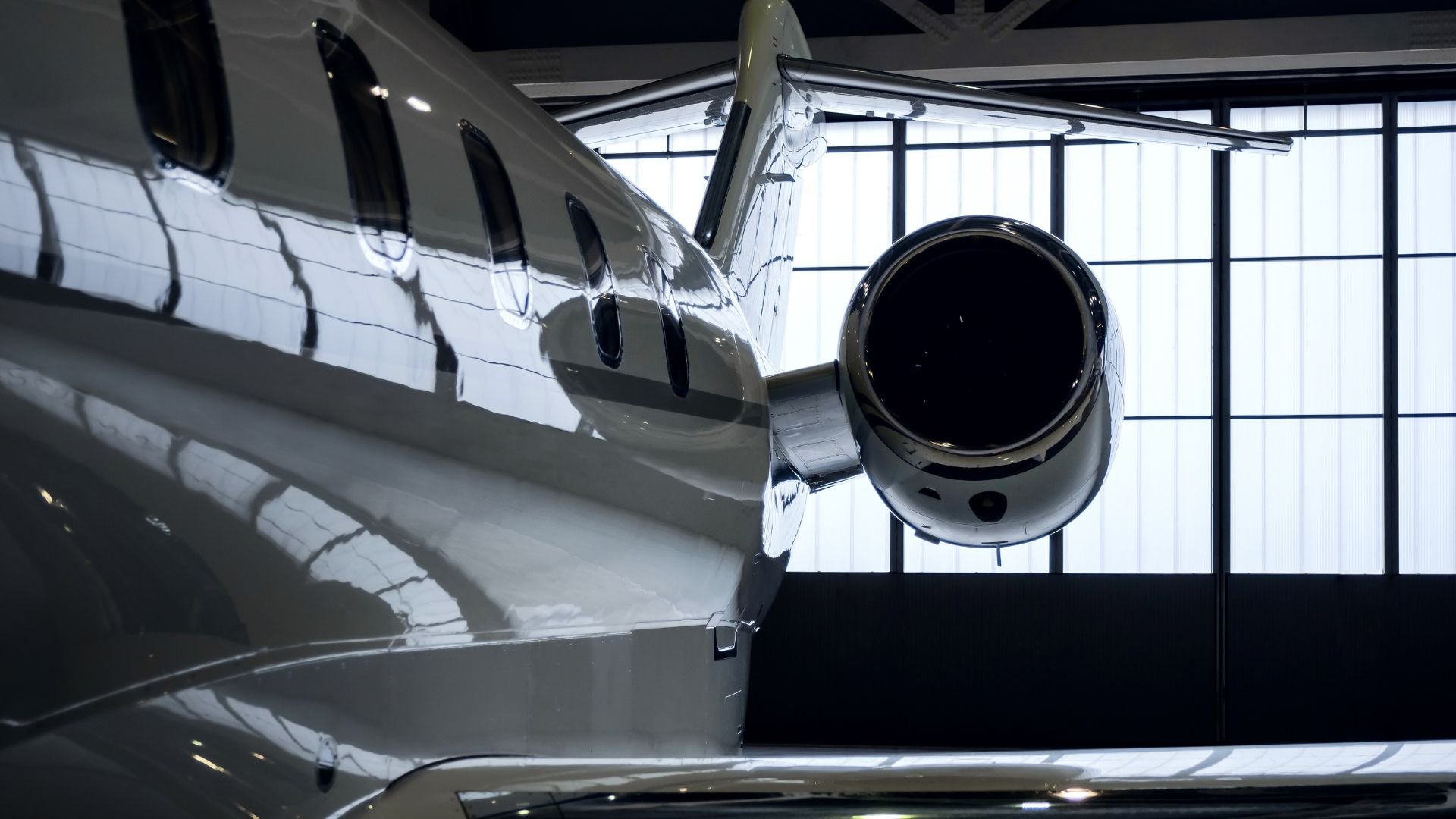 Sleek private jet parked in a hangar with reflective metallic surface