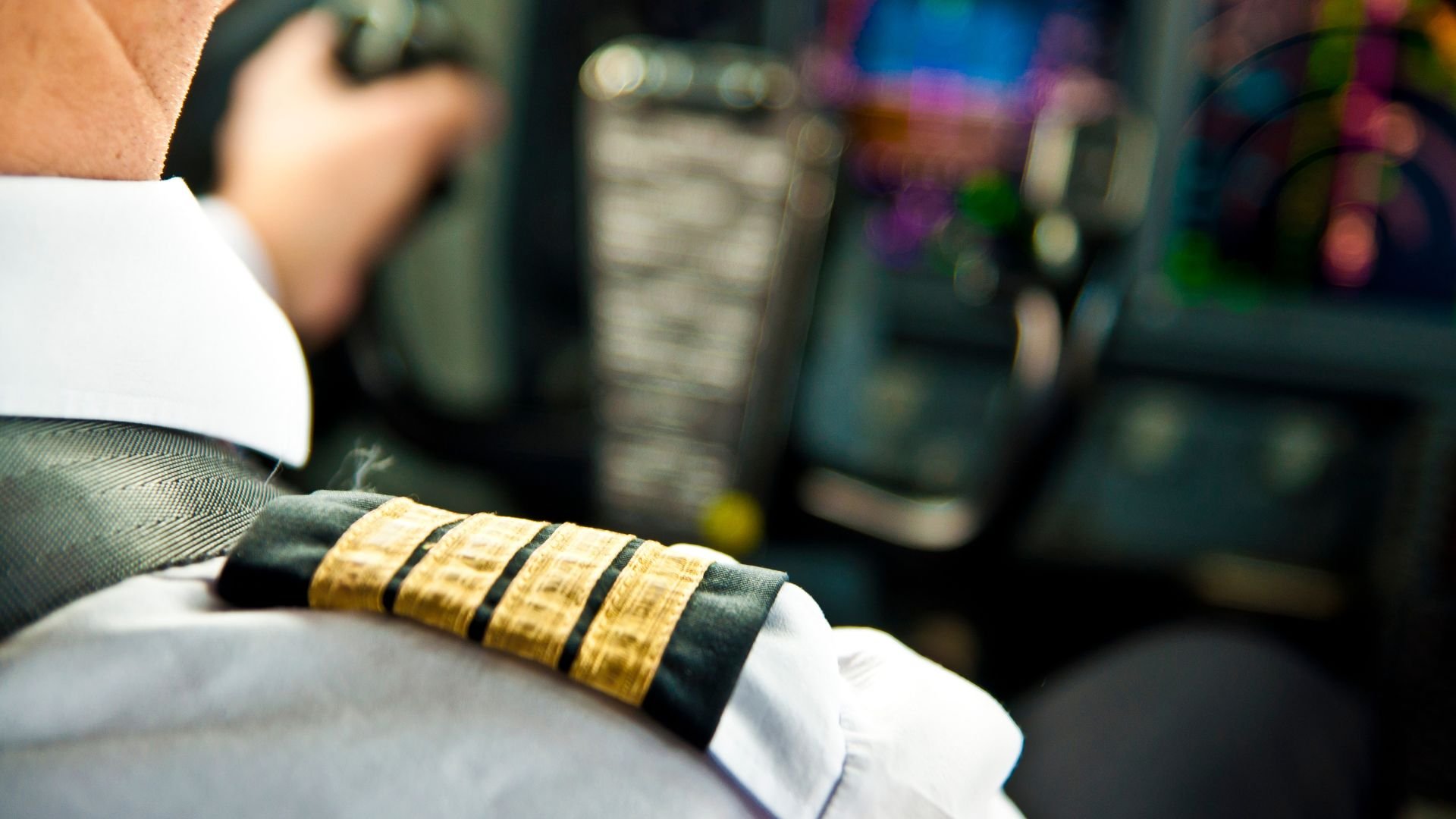 Pilot's sleeve with gold rank stripes in aircraft cockpit
