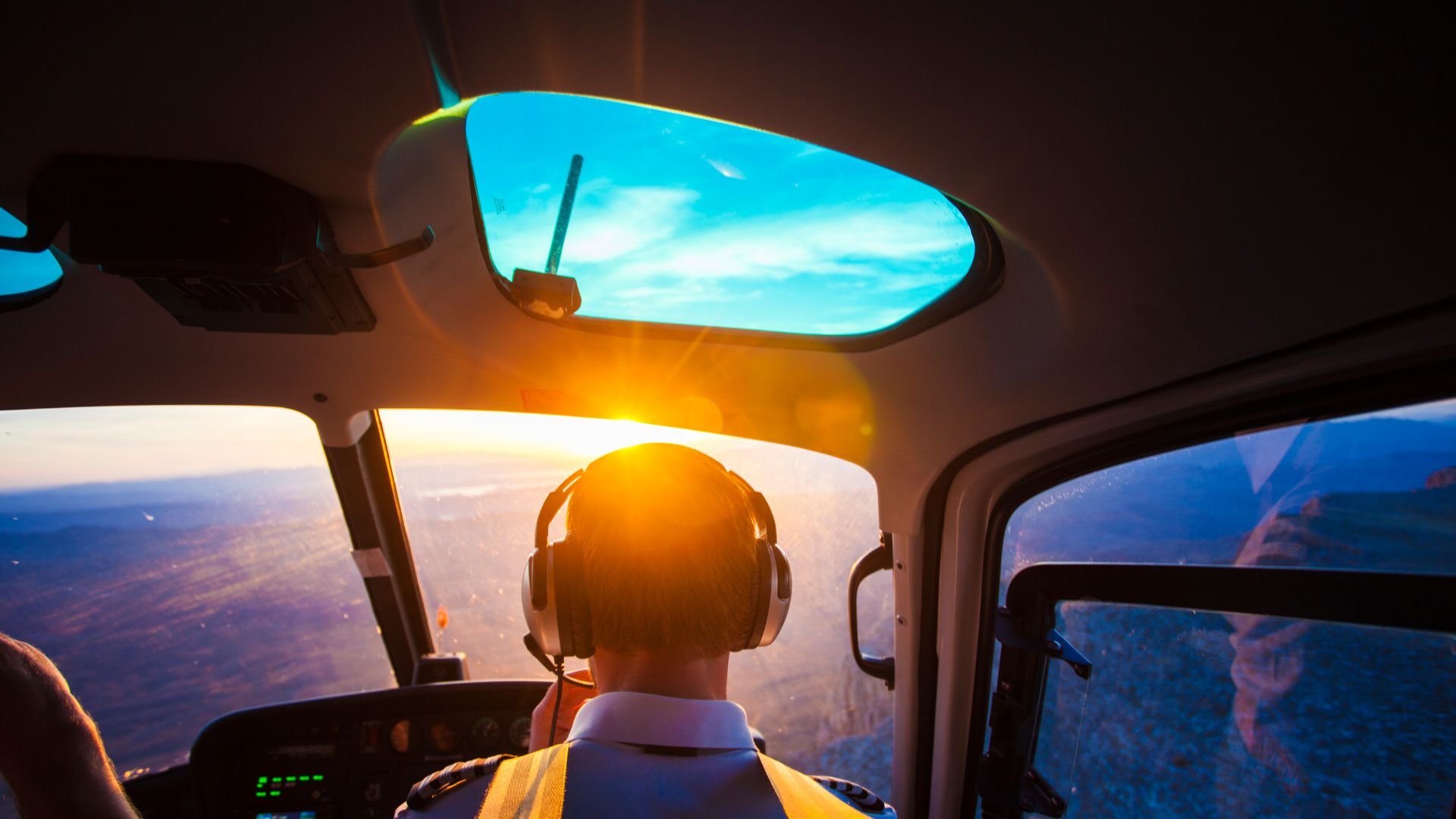 Pilot wearing headphones flying aircraft during golden hour sunset